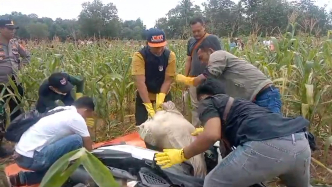 Polisi mengevakuasi mayat perempuan terbungkus karung.