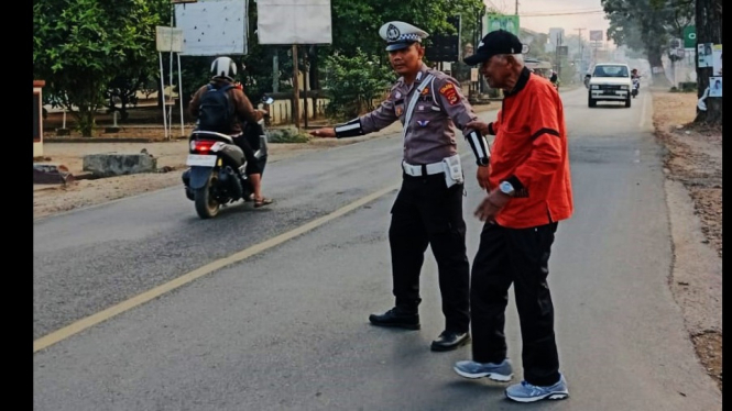 Personel Polres Lampung Timur membantu warga menyeberang jalan.