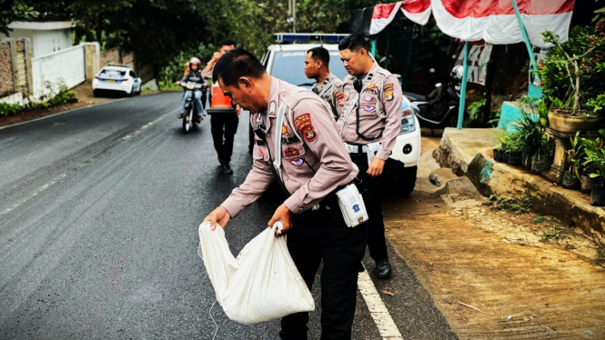 Polisi menutupi area tumpahan solar menggunakan pasir.