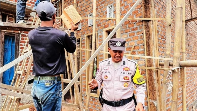 Aipda Hendri Siswanto membantu warga membangun rumah.