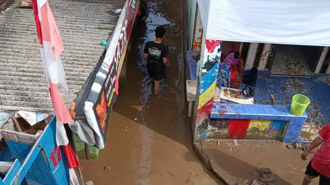 Warga berjalan di lumpur banjir