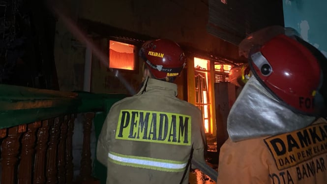 Petugas pemadam kebakaran memadamkan api di rumah warga.