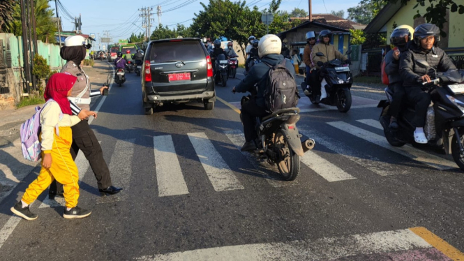 Satlantas Polres Pesawaran bantu sebrangkan pelajar ke sekolah.