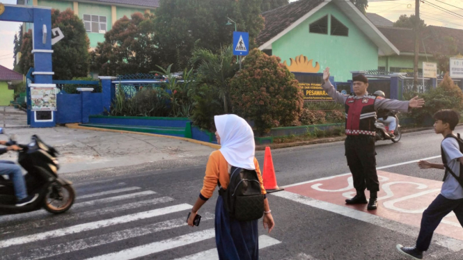 Polsek Gedong Tataan bantu pelajar menyeberang ke sekolah.
