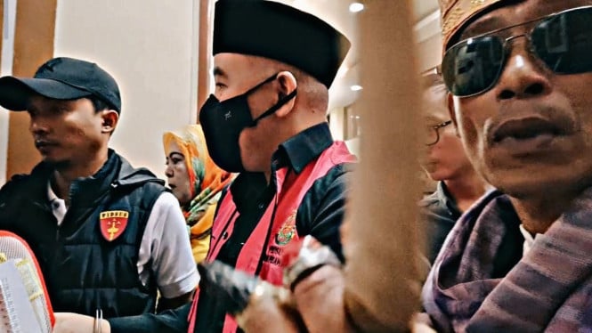 Pelaku yang diduga memukul ponsel jurnalis menggunakan kacamata