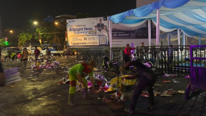 Petugas Dinas Lingkungan Hidup (DLH) Kota Bandar Lampung membersihkan sampah sisa nobar Final Piala Dunia 2026 di Tugu Adipura.
