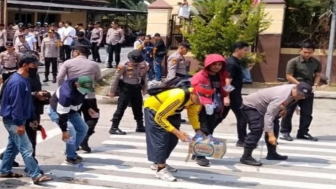 Polisi punguti sampah usai unjuk rasa Karyawan PT. BSA di depan Mapolda Lampung.