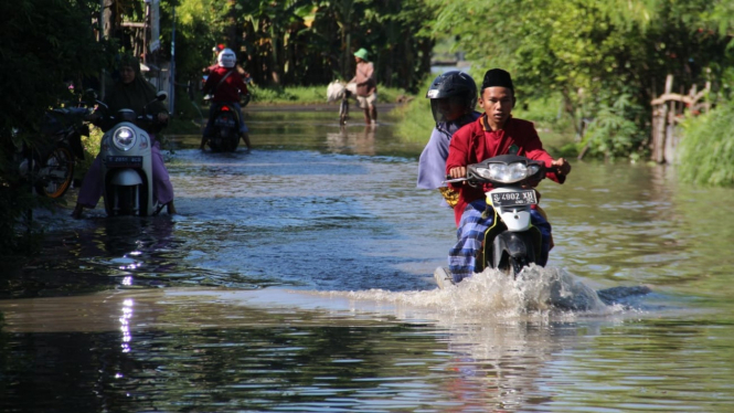 Warga Saat melintasi banjir di Desa Tugu Sumberejo, Jombang.