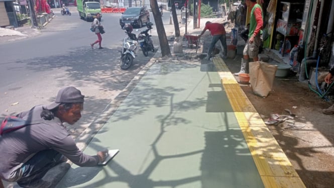 Pekerja saat melakukan pemerataan trotoar di Kota Batu.