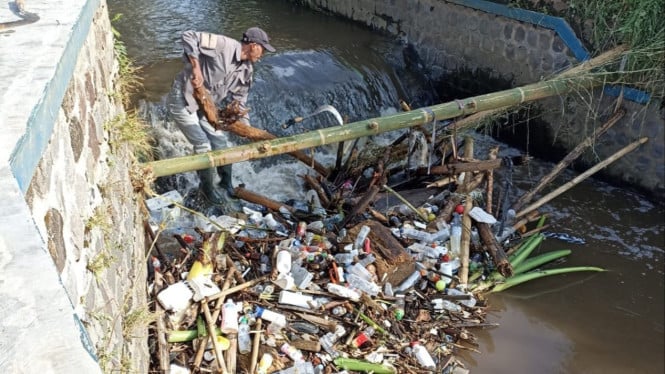 Petugas membersihkan sampah di aliran Kali Paron