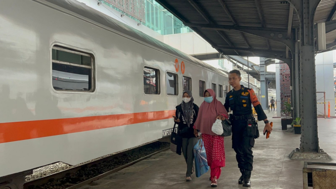 Petugas membantu penumpang bergegas naik kereta api.