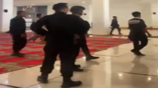 Personel polisi memakai sepatu masuk  di Masjid Raya Sumbar.