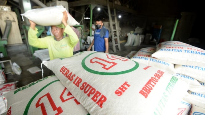 Pekerja sedang mengangkat beras di kilang padi.