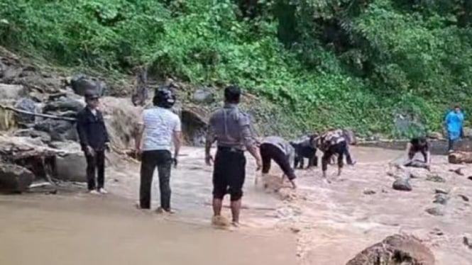 Petugas bersama warga membersihkan material longsor yang menutupi jalan lintas Simalungun.