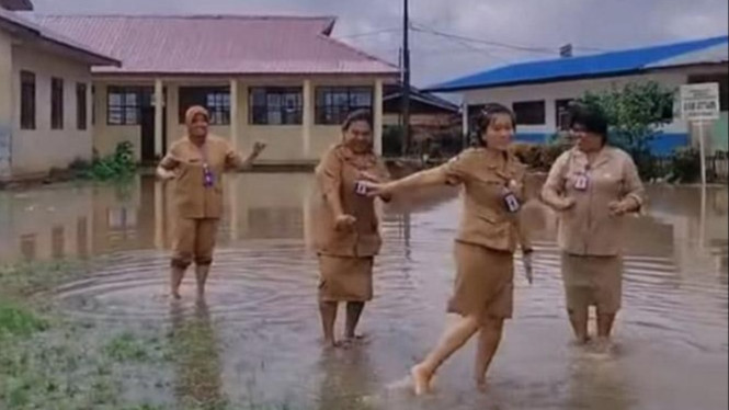 Aksi kepsek di Karo bersama sejumlah guru bermain banjir di halaman sekolah.