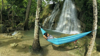 Pengunjung menikmati suasana Air Terjun Randusari sambil tiduran.