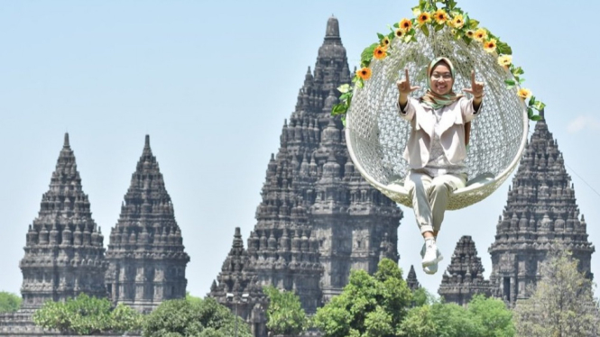 Wisatawan berfoto membelakangi Candi Prambanan.