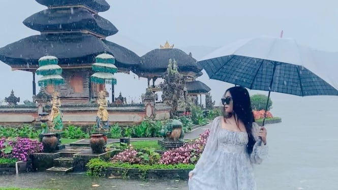 Wisatawan menikmati pemandangan wisata Bali saat cuaca hujan.