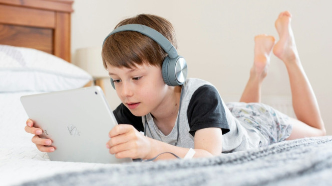 Anak menggunakan headphone
