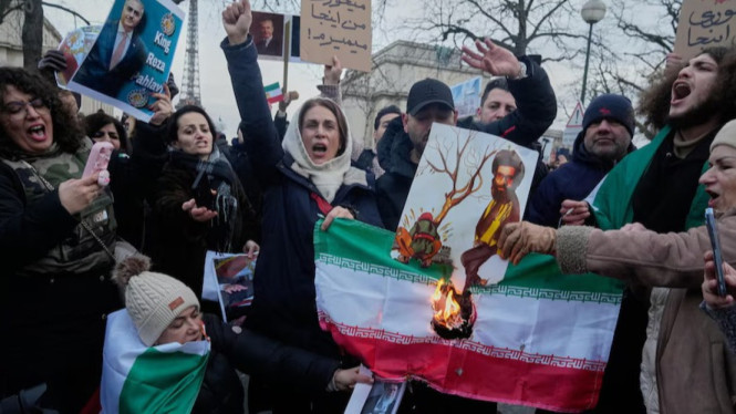 Para demonstran di Paris sedang membakar bendera Iran