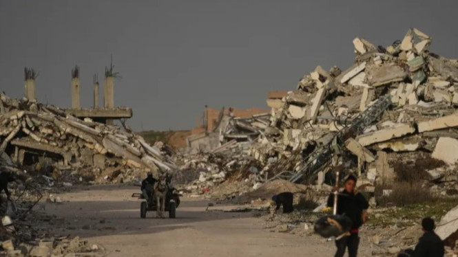 Warga Palestina berjalan di tengah reruntuhan