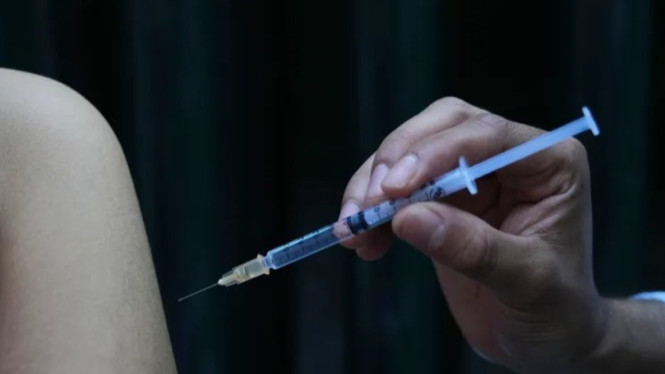 Seorang petugas kesehatan memberikan dosis vaksin campak