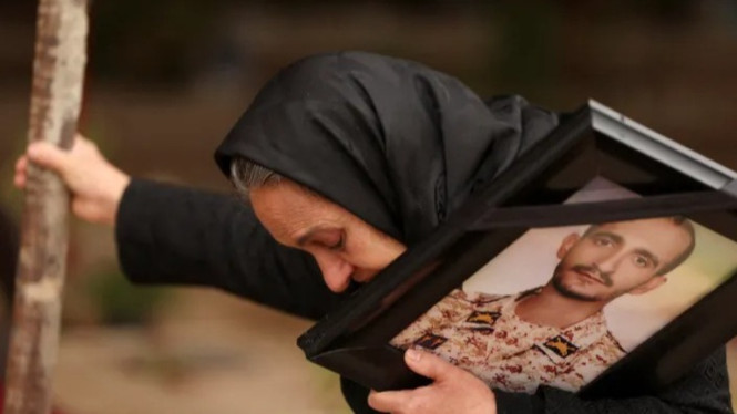 Marzia Rezaei bereaksi sambil berdiri di dekat makam putranya, Erfan