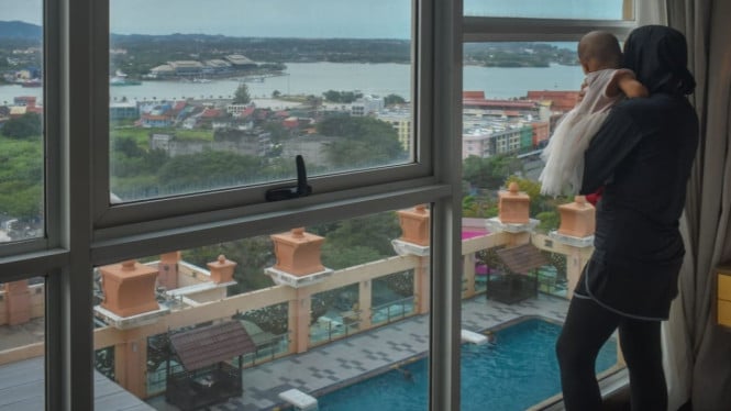 Ibu dan bayi menikmati pemandangan dari jendela kamar hotel
