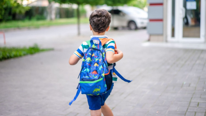 anak laki-laki dengan tas punggung yang sedang berjalan