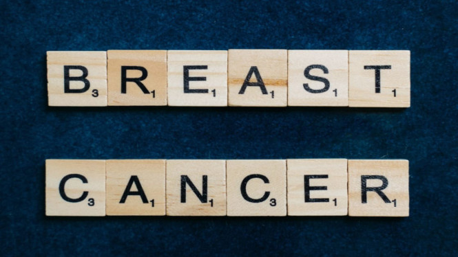 scrabble kayu bertuliskan "kanker payudara" dengan background warna gelap