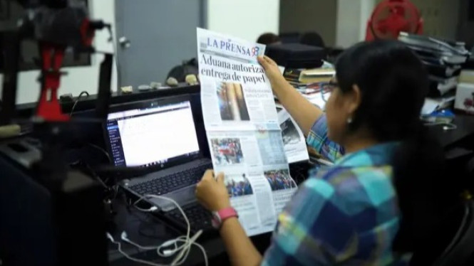 Seorang perempuan sedang membaca koran La Prensa