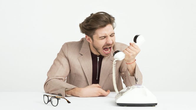 Seseorang dengan ekspresi mengumpat di telepon.