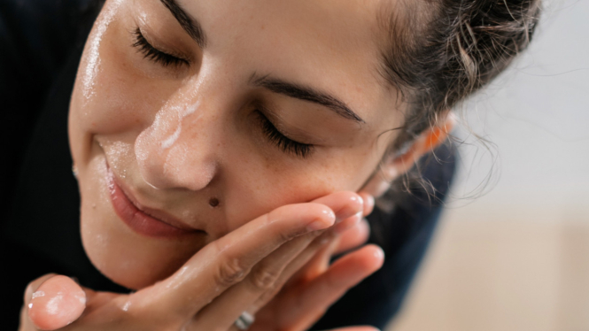 Ilustrasi wanita yang memiliki kulit sensitif sedang mencuci muka.