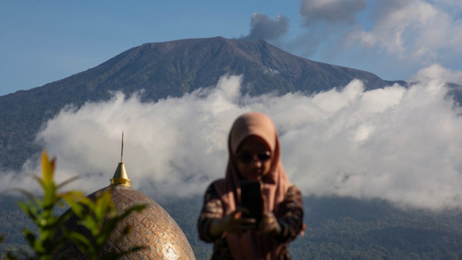 Warga berswafoto berlatar belakang gunung Marapi yang sedang Erupsi