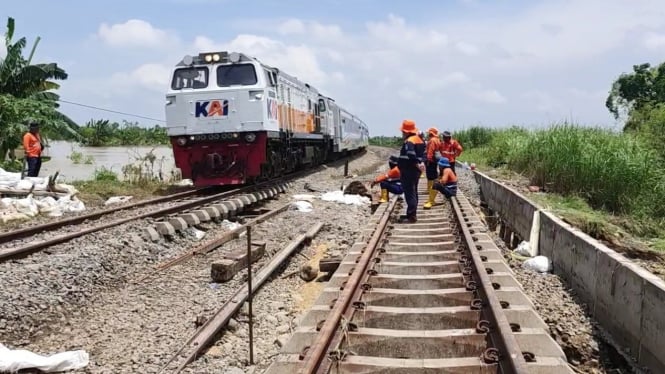 Kereta api melewati jalur yang diperbaiki karena banjir.