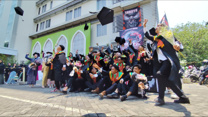 Wisudawan Unissula Semarang merayakan wisuda di depan kampus.