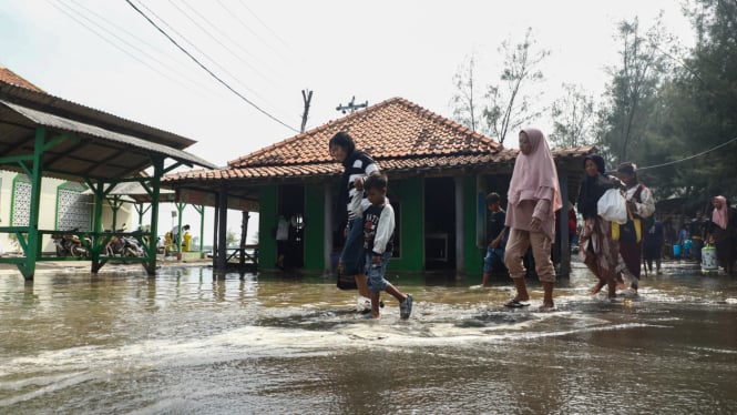 Warga Pemalang melewati genangan rob.