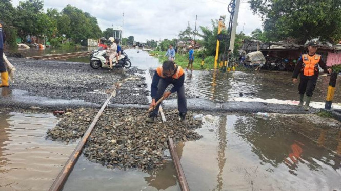 Petugas KAI sedang memulihkan jalur rel tergenang banjir.