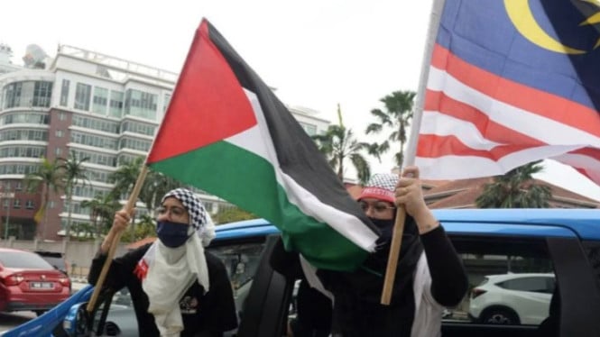 Pengunjuk rasa membawa bendera Palestina dan Malaysia