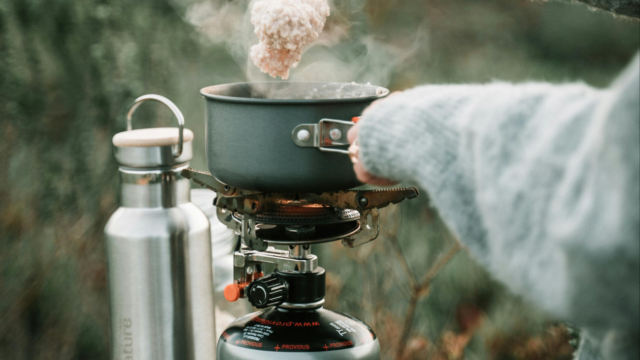 A Person Cooking Oatmeal using Portable Stove